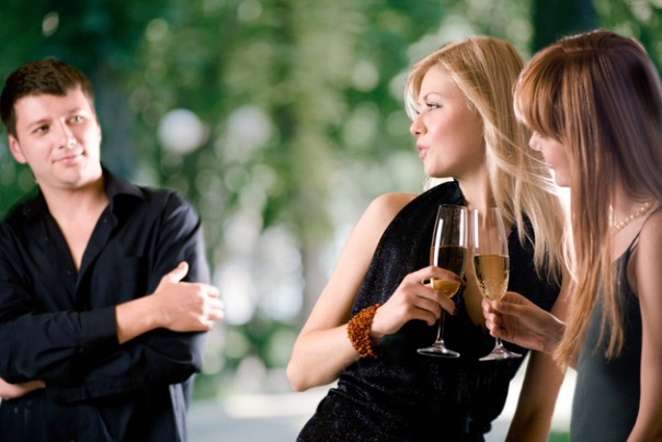 Two women holding glasses with champagne and laughing, young man